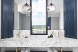 The master bathroom is designed with Carrara marble counters, blue cabinets and brass hardware sinks. 