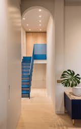 A glimpse of the iridescent blue aluminium staircase through an arched doorway leads up to the Master Suite