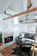 Living Room, Corner Fireplace, Sofa, and Medium Hardwood Floor Electric Fireplace in Urban Park Studio tiny home.  Features a storage couch bed.    Photo 1 of 18 in Tiny Home & ADU - Open Living by Tru Form Tiny