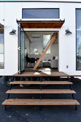 Folding door on a an Urban Park Studio by Tru Form Tiny.  Features a custom stair system, shallow ladder, Rejuvenation lighting, and White Paneling