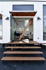 Folding door on a an Urban Park Studio by Tru Form Tiny.  Features a custom stair system, shallow ladder, Rejuvenation lighting, and White Paneling