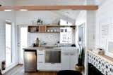 Kitchen, Wood Counter, Ceramic Tile Backsplashe, Refrigerator, Range Hood, Ceiling Lighting, Medium Hardwood Floor, Recessed Lighting, White Cabinet, Wood Cabinet, Cooktops, Drop In Sink, and Dishwasher Tiny kitchen in a Tru Form Tiny, Urban Park Studio. Features a hickory kitchen shelf, organic white tile, butcher block counters, apron front sink, and farmhouse accents.    Photo 18 of 18 in Tiny Home & ADU - Open Living by Tru Form Tiny