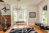 The main entrance to the Empress showcasing the original pine plank flooring, windows, walnut staircase, 14inch baseboards and 8ft front glass doors. The crystal chandelier is hanging from the original plaster ceiling mount.