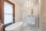 The master bath has white marble flooring with a large soaker tub, walk in shower and mother of pearl tile surround. The vanity has a white quartz top with crystal handles on the faucets.