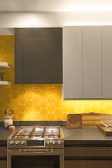 In the kitchen, the designers also considered lighting design with cabinet lighting both under and above the cabinets. The backsplash tile is by Fireclay Tile. The hood range is custom wrapped in blackened steel by Joe Chambers. 