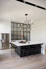 The minimal and functional kitchen features a built-in island that seats 5-6, but more often it serves as a prep-working surface for catered parties. Behind the kitchen is a pantry room divided by a full ceiling-height glass wall, glazed with frosted glass and bound by a steel frame. 