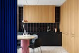 The kitchen area is accomplished in the oak veneer to feel cosier and get extra soft-touch feelings. Black ceramic backdrop with pinkish seams serves as a subframe to the wooden facades. The customized dining table is lit by a Flowerpot lamp designed by Verner Panton in 1968.