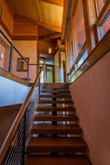 The stairway features floating treads of Brazilian ipe wood, handrails with stainless steel wire rope, and walls with colored clay finish.