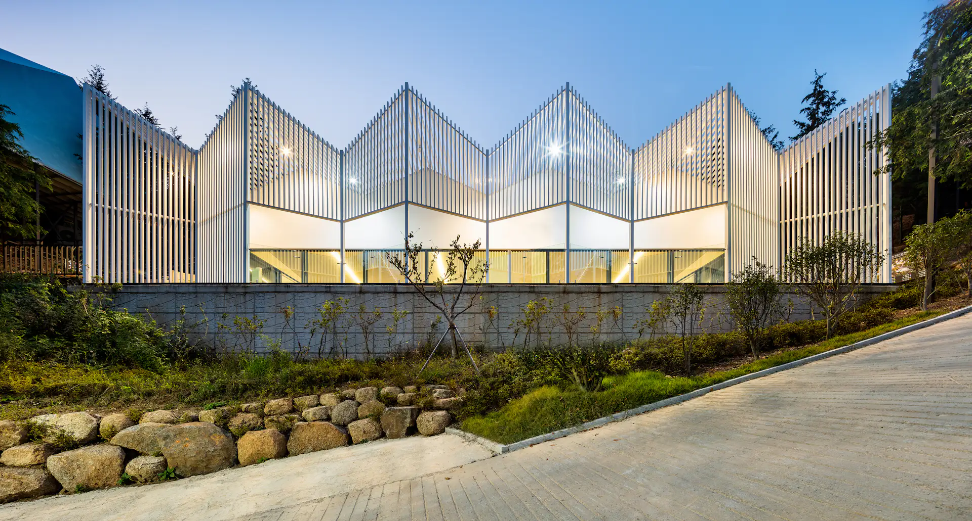 The community facility is formed of geometric shapes featuring white louvres made from steel.