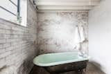 Housed underneath the mezzanine level, the bathroom features whitewashed walls and an elegant, freestanding bath.
