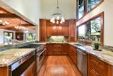 Kitchen, Dishwasher, Microwave, Medium Hardwood Floor, Wood Cabinet, Track Lighting, Ceiling Lighting, and Cooktops Open kitchen with stainless steel Wolf appliances.  Photo 17 of 18 in Modern Craftsman Amongst Redwoods by Mimi Goh