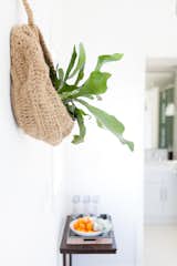 Behind the desk and host chair, two woven jute baskets hold a duo of staghorn ferns.