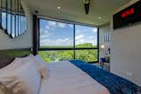 The guest bedroom features floor-to-ceiling windows overlooking Tulum National Park.