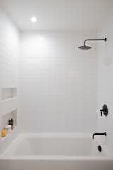 Each bathroom features matte black hardware and oversized Phylrich rain shower heads.