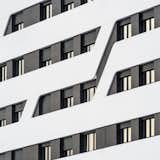 Detail of the façade, with dark ceramic Stonker and horizontal bands coated with white Krion