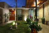 Outdoor, Stone Fences, Wall, Grass, Trees, Garden, Flowers, Wood Patio, Porch, Deck, Hanging Lighting, and Tile Patio, Porch, Deck Courtyard  Photo 3 of 15 in COME IN! Family is in the courtyard by Vera + Ormaza Arquitectos