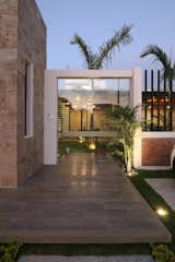 Outdoor, Concrete Fences, Wall, Grass, Trees, Garden, Tile Patio, Porch, Deck, Hanging Lighting, Concrete Patio, Porch, Deck, Metal Fences, Wall, Wood Fences, Wall, and Wood Patio, Porch, Deck Entrance  Photo 11 of 15 in COME IN! Family is in the courtyard by Vera + Ormaza Arquitectos