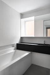 White square ceramic tiles cover the bathroom walls. The counters are Fenix Laminate (Arpa).