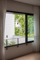 Bedroom, Medium Hardwood Floor, and Ceiling Lighting Looking across the Courtyard, nested in the concrete band, is a framed view of the trees in the vicinity.  Photo 14 of 22 in Trio Stack (a.k.a Project #10) by Studio Wills + Architects