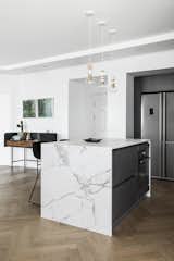 This apartment, overlooking the beautiful beach and the urban views of Tel Aviv, was built in the late 1990s and hadn't been renovated since, until designer Maya Sheinberger came in. The kitchen cabinets were chosen in a grey color with a matte finish and for the countertops, the designer chose a bright Dekton with marble texture. Above the kitchen island, which is used for cooking and for light family meals, are three wooden lighting fixtures by Israeli designer Ohad Benit.