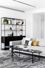 Living Room, Track Lighting, Chair, Sofa, Bookcase, Concrete Floor, Coffee Tables, End Tables, Ottomans, and Carpet Floor The living room  Photo 17 of 29 in C Apartment by Maya Sheinberger