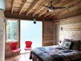 Bedroom, Bed, Chair, Cork Floor, and Pendant Lighting The bedrooms are enclosed with the Western Red Cedar structure and siding, featuring reclaimed frosted glass and operable windows.  Photo 5 of 15 in Glass Cabin | an off-grid family retreat by Steven Risting
