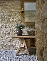 In the bathroom the exposed stone walls form the background of a rustic timber vanity counter