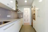 Kitchen, Microwave, Range, Ceramic Tile Floor, Wall Oven, White Cabinet, Ceiling Lighting, Marble Counter, Stone Slab Backsplashe, Refrigerator, Dishwasher, Cooktops, Range Hood, and Drop In Sink  Photo 4 of 12 in Rosselló St., Eixample, Barcelona by Marina Sezam