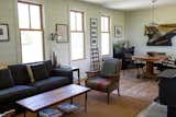 Living room with wood burning stove, open dining area with stocked bar and piano art.