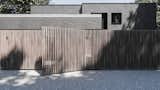 Massive wooden fence, which is a stripe, is on the background of a brick house, which is a square.