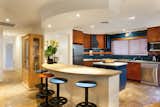 Kitchen with bar stools and spanish stone table top, includes dishwasher, microwave, cook top,oven and fridge.