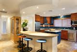 Kitchen with bar stools and spanish stone table top, includes dishwasher, microwave, cook top,oven and fridge.