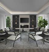The spacious great room in this Franklin home, completed in 2017, is open to the kitchen and features a linear fireplace on a floating honed limestone hearth, supported by hidden steel brackets, extending the full width between the two floor to ceiling windows.  The custom oak shelving forms a display case with individual lights for each section allowing the homeowners to showcase favorite art objects.  The ceiling features a step and hidden LED cove lighting to provide a visual separation for this area from the adjacent kitchen and informal dining areas.  The rug and furniture were selected by the homeowners for everyday comfort as this is the main TV watching and hangout room in the home.  A casual dining area provides seating for 6 or more and can also function as a game table.  In the background is the 3 seasons room accessed by a floor-to-ceiling sliding door that opens 2/3 to provide easy flow for entertaining. 