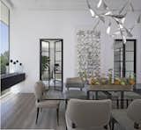 The dining room is the first room seen from the entry and is designed to provide unobstructed views of the lake and greenery through it’s 12’ high floor to ceiling and wall-to-wall glazing.  A buffet for serving and storage seems to float in the 14’ width which was accomplished with a steel beam concealed within the cabinetry.  The owner of this Franklin home, completed in 2017, selected the light fixture early in the design process and wanted to ensure the rest of the design was clean and that this was a focal point.  The ceiling features a reveal in the drywall around the perimeter along with layered dry-wall on the ceiling to create an interesting but subtle texture.  The dining room has access to the kitchen, through two extra deep dry-walled arches.  Access to the adjacent sitting room through two pairs of custom steel and glass French doors.  