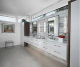 The master bath in this Franklin home, completed in 2017, features a natural cement looking porcelain floor tile with large format Italian porcelain slabs on the walls to create a natural gray travertine appearance.  The wall hung cabinetry is simple yet functional allowing for all items including towels, linens, and dirty laundry to be easily stored in the two towers flanking the countertop.  Above the two towers is a ribbon of glass windows to the ceiling which provide ample light while allowing for privacy.  The bathroom also features a makeup vanity area with built-in hidden medicine cabinets and a huge walk-in shower with rain head, floating stone seat, and matching floor-to ceiling porcelain slabs on the shower walls.