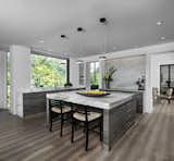 The owners goal with their Franklin homes kitchen, completed in 2017, was to emphasize the beautiful lake views and have a space that was open to a large family room and casual dining area.  This contemporary kitchen combines convenience and function with hidden small appliances including a coffee station, toaster oven, microwave, to avoid cluttered countertops ensuring a clean look.  The cooking area features an induction cooktop, mixer and a full quartz backsplash, as well as a hidden ventilation and lighting system in the soffit.  A focal point is the large island which provides ample seating while leaving plenty of room for cooking and baking.  Quartz was chosen for its beauty, durability, and ease of maintenance.  The cabinetry features an integrated refrigerator, freezer, and dishwasher which complete the clean, uncluttered look.  The kitchen also features two openings to the formal dining room providing easy flow and access for entertaining.  