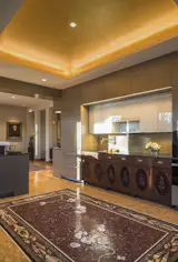 Gallery-like walls of family portraits in the dining room complement the wood, tile, and golden richness of the kitche. Casework is understated to the point of feeling like surfaces, not cabinets.