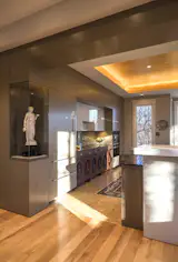 An art display case makes the transition from dining to kitche. Cabinetry is extended without toekicks from floor to ceiling to feel like gallery walls.