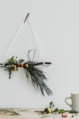 This simple, chic modern holiday decor makes for an easy DIY project. Gather your favorite greenery and a sturdy twig, and bind them together with a copper band for a metallic accent—or your favorite ribbon. For a more classic Christmas vibe, add a poinsettia into the mix.&nbsp;