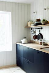 Dark cabinets juxtapose with white shiplap in this simple, functional kitchen. Solar power supplies the electric range top.