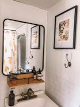 Jacqueline modernized the run-down RV bathroom with white peel-and-stick subway tile from Smart Tiles and a few coats of white paint on the dated brown walls. A brushed nickel faucet and garment hook complete the chic look, along with the wooden shelf above the sink.