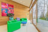 A pair of Mid-Century-style neon green chairs are positioned in front of the floor-to-ceiling windows peering out to the beachfront.