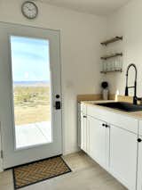 Kitchen, Wood Counter, Wood Backsplashe, Light Hardwood Floor, Recessed Lighting, White Cabinet, Microwave, Refrigerator, Drop In Sink, and Ceiling Lighting Every room has access to natural light and sweeping views.  Photo 2 of 6 in The Bell Cabin by Ida Alwin