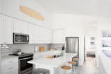 Kitchen, Refrigerator, Range, Engineered Quartz Counter, White Cabinet, Vinyl Floor, Microwave, Ceiling Lighting, Subway Tile Backsplashe, and Drop In Sink  Photo 6 of 9 in S A L T - A Coastal Modern Townhome by Theo Milo
