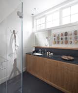 The master bathroom provides additional display space, and continues the vocabulary of cherry and infusion of nature light.