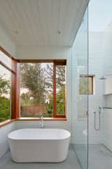 A large skylight above the shower and a generous sliding glass panel open the bathroom to the landscape beyond, creating an indoor-outdoor bathing experience.