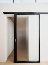 Custom steel and fluted glass barn doors provide privacy to both the office and the adjacent den, while also allowing shared light from the large fenestration at the main living space to filter through.