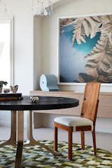 The dining table’s juxtaposition of solid brass base and charred oak top is complimented by the vintage pine dining chairs by Axel Einar Hjorth.