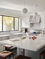 The kitchen dons white marbled quartz countertops and backsplash, Wolf range appliances,  Cassina stools and hardwood floors.