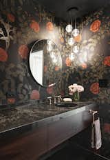 An elegant powder room.
A dark, red rose accented, Timorous Beasties wallpaper wraps the intimate powder room. While, a custom vanity, quartz countertop and Bocci pendant light create an immersive ambience.